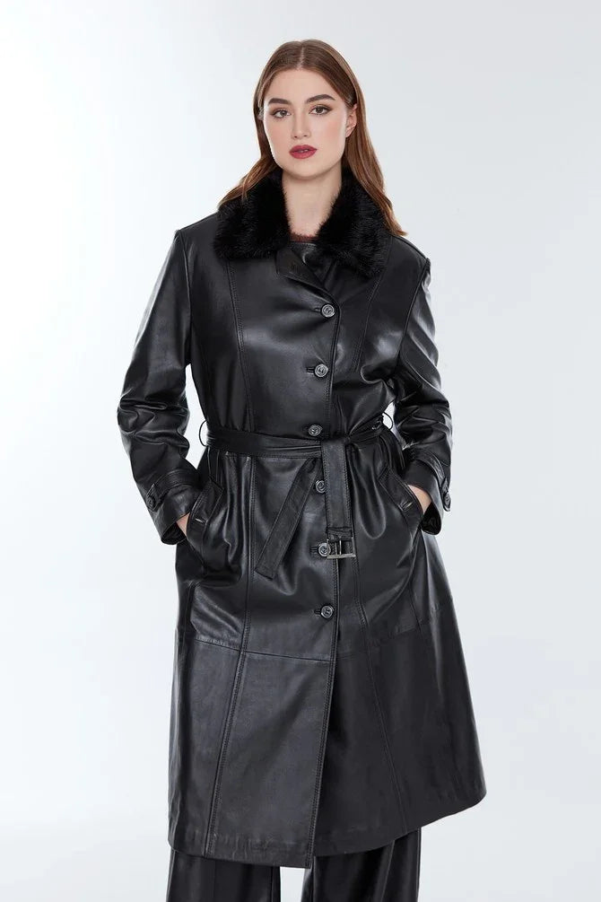 Woman wearing long black leather coat with belt and fur collar, hands in pockets
