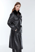 Woman wearing long black distressed leather jacket with belt and faux fur collar